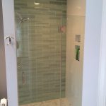 Custom tiled shower with glass accent wall, marble tile floor and custom glass door 